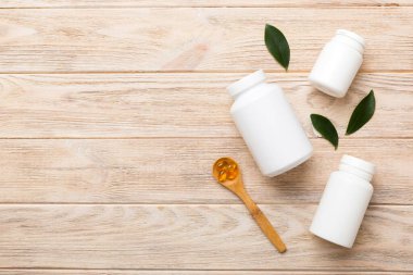 Omega-3 kapsülleri yeşil yapraklı arka planda beyaz bir şişede yatar. Balık yağı tabletleri. Biyolojik olarak aktif katkı maddeleri. Omega 6, Omega 9, A vitamini, E, D vitamini, D3 vitamini..