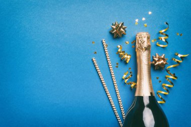 Gözlüklü bir şişe şampanya ve renkli arka planda renkli konfeti. Üst görünüm yatıyordu.