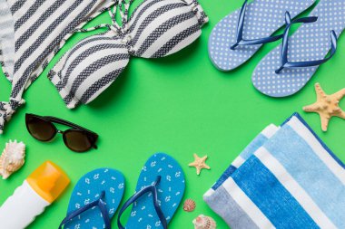 Kadın mayo ve plaj aksesuarları renkli arka plan yaz seyahati konseptine düz bir görünüm kazandırıyordu. Bikini mayo, hasır şapka ve deniz topuklu ayakkabı. Üst görünümü kopyala.