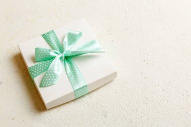 Renkli arka planda mor kurdeleli Noel ya da diğer tatil hediyelerini kağıda sardım. Şimdiki kutu, renkli tabloda hediye süslemesi, kopya alanı ile üst görünüm.