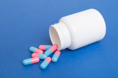 İlaç şişesinden alınan farklı uyuşturucu ve sağlık takviyesi hapları ve renkli arka plana ilişkin tıbbi genel görünüm.