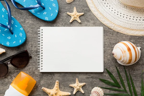 Blank writing book with summer beach accessories on background, copy space. Flat lay with copy space.