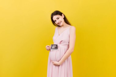 Bebek Sonografisi Fotoğraflı Tatlı Hamile Kadın Pozu Renkli Arkaplan. Hamilelik kavramı, jinekoloji, tıbbi test, annelik sağlığı.
