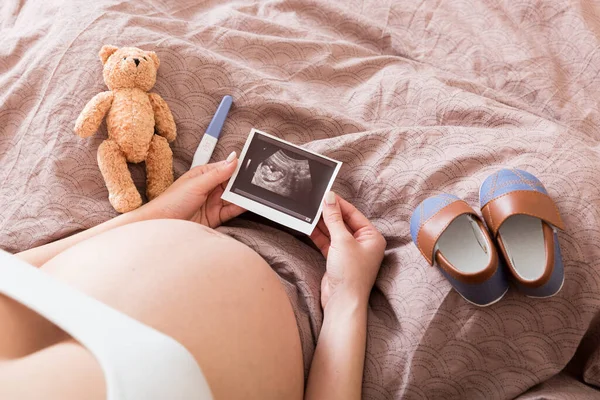 Kobieta Ciąży Siedzi Łóżku Patrzy Zdjęcie Usg Swojego Dziecka Ciężarna — Zdjęcie stockowe