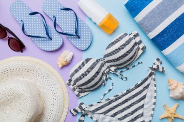 Kadın mayo ve plaj aksesuarları renkli arka plan yaz seyahati konseptine düz bir görünüm kazandırıyordu. Bikini mayo, hasır şapka ve deniz topuklu ayakkabı. Üst görünümü kopyala.