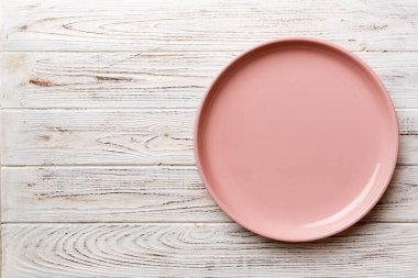 Ahşap arka planda boş pembe tabağın üst görüntüsü. Tasarımın için boş boşluk.