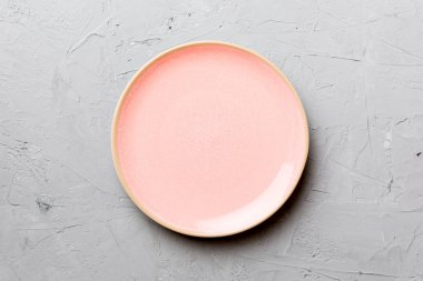 Çimento arka planındaki boş pembe tabağın üst görüntüsü. Tasarımın için boş boşluk.
