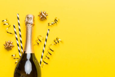 Gözlüklü bir şişe şampanya ve renkli arka planda renkli konfeti. Üst görünüm yatıyordu.