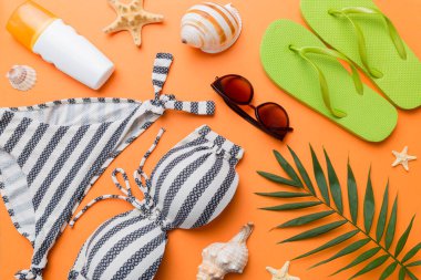 Kadın mayo ve plaj aksesuarları renkli arka plan yaz seyahati konseptine düz bir görünüm kazandırıyordu. Bikini mayo, hasır şapka ve deniz topuklu ayakkabı. Üst görünümü kopyala.