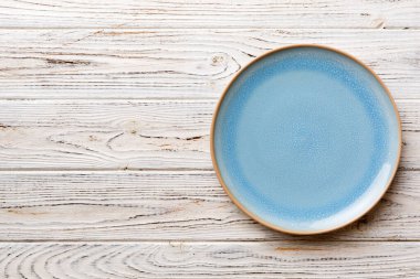Ahşap zemindeki boş mavi tabağın üst görüntüsü. Tasarımın için boş boşluk.