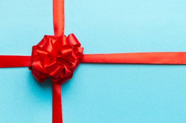 Kırmızı kurdelenin üst görüntüsü yuvarlandı ve kırmızı fiyonk renkli arka planda izole edildi. Kopyalama alanı olan düz.