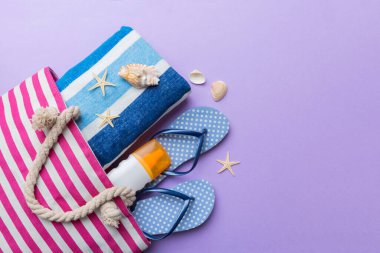 Plaj aksesuarları renkli arka plan yaz seyahati konseptinde düz bir görünüm sergiliyordu. İçinde deniz yıldızı ve deniz kabuğu olan bir çanta. Üst görünüm.