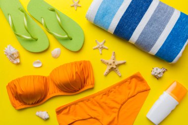Kadın mayo ve plaj aksesuarları renkli arka plan yaz seyahati konseptine düz bir görünüm kazandırıyordu. Bikini mayo, hasır şapka ve deniz topuklu ayakkabı. Üst görünümü kopyala.