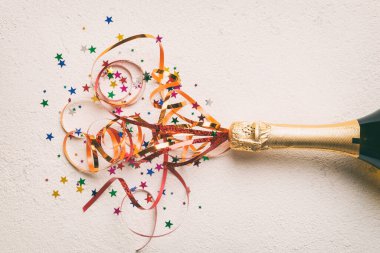 Yaratıcı düz kompozisyon, bir şişe şampanya ve renkli arka plan üzerine yazı için yer. Renkli parti flamalarıyla şampanya şişesi. tatil ya da noel konsepti.