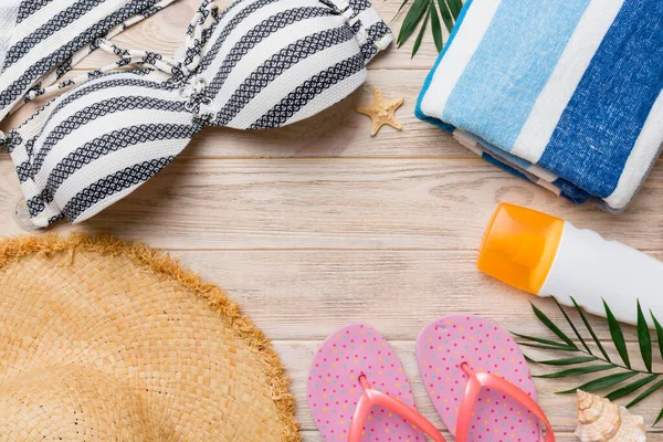 Woman swimwear and beach accessories flat lay top view on colored background Summer travel concept. bikini swimsuit, straw hat and seasheels. Copy space Top view.