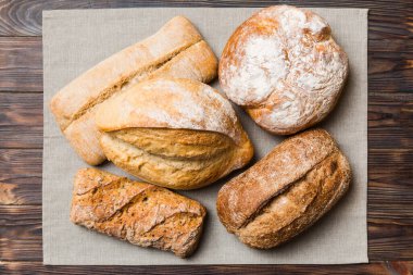 Kırsal masa manzaralı peçeteli taze pişmiş ekmek çeşitleri. Sağlıklı mayasız ekmek. Fransız ekmeği.