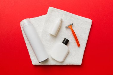 Tıraş Adam seti. Traş makinesi, havlu, losyon ve renkli arka planda tıraş köpüğü. Erkekler banyo aksesuarları üst görünüm.