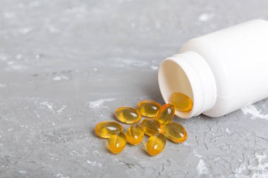 Omega-3 kapsülleri masa arkasında beyaz bir şişede yatıyor. Balık yağı tabletlerinin üst görüntüsü. Biyolojik olarak aktif katkı maddeleri. omega 6, omega 9, A vitamini, D vitamini, D3 vitamini, akşam çuha çiçeği yağı.