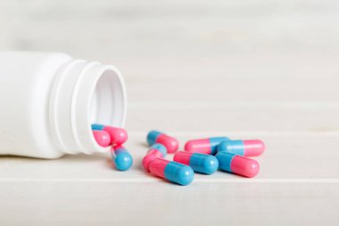 Renkli arka planda haplarla dolu plastik ilaç şişesi. İnternetteki eczane. Ağrı kesici ilaç ve antibiyotik ilaç direnci konsepti. İlaç endüstrisi..