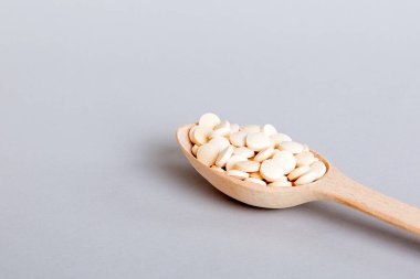 Renkli arka planda bir yığın beyaz hap. Tabletler masaya saçılmış. Kırmızı yumuşak jelatin kapsül yığını. Vitaminler ve beslenme takviyeleri konsepti.