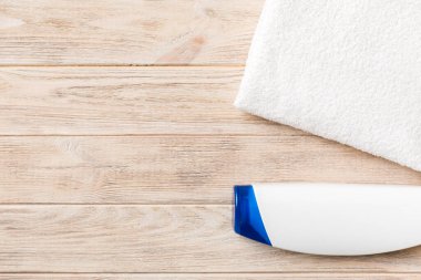 Kozmetik şampuan şişesi renkli bir masada havluyla birlikte. Banyo arka planı, el ve vücut bakımı için tuvalet aksesuarları..