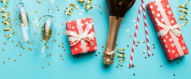 Renkli simli bir şişe şampanya, konfeti ve renkli arka planda metin için hediye kutusu alanı, üst manzara. Komik, noel ve doğum günü kutlaması.