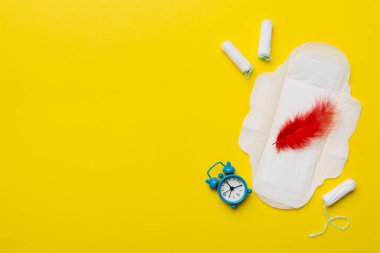 Alarm saatini hijyenik kadın tamponları ve regl pedleri ile çalıyor. Tıbbi konsept kadın kritik günler ve regl dönemi. Kadın günlük hijyen. Boşluğu kopyala.