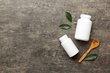 Omega-3 kapsülleri yeşil yapraklı arka planda beyaz bir şişede yatar. Balık yağı tabletleri. Biyolojik olarak aktif katkı maddeleri. Omega 6, Omega 9, A vitamini, E, D vitamini, D3 vitamini..