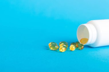 Yumuşak jel hapları ve Omega-3 yağı hap şişesinden sızıyor. Jel kapsülleri beyaz yüzey şişesi. Omega 3, multivitamin, kalsiyum, antibiyotik. Sağlığa. Dokunulmazlık.