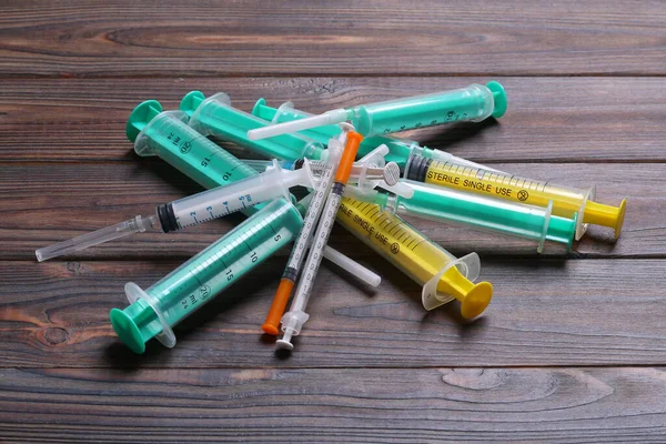 Top view of a pile of syringes and insulin syringes ready for injection at wooden background. Health care concept with copy space.