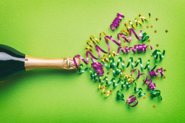 Yaratıcı düz kompozisyon, bir şişe şampanya ve renkli arka plan üzerine yazı için yer. Renkli parti flamalarıyla şampanya şişesi. tatil ya da noel konsepti.