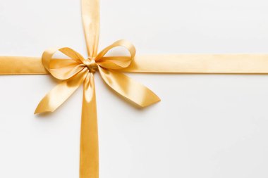 Altın kurdelenin üst görüntüsü yuvarlandı ve sarıyay renkli arka planda izole edildi. Kopyalama alanı olan düz.