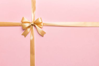 Altın kurdelenin üst görüntüsü yuvarlandı ve sarıyay renkli arka planda izole edildi. Kopyalama alanı olan düz.