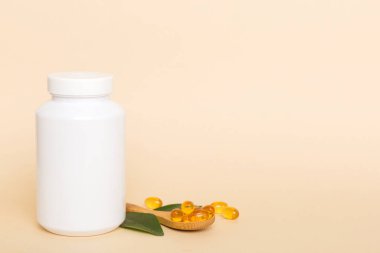 Omega-3 kapsülleri yeşil yapraklı arka planda beyaz bir şişede yatar. Balık yağı tabletleri. Biyolojik olarak aktif katkı maddeleri. Omega 6, Omega 9, A vitamini, E, D vitamini, D3 vitamini..
