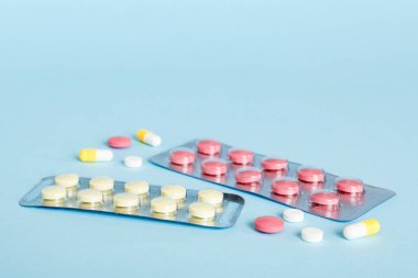 Renkli vitaminli kabarcık paketi. Arka planda ilaç hapları. İlaçlar ve reçeteli haplar arka plandaydı. Su toplamış pembe tıbbi haplar..