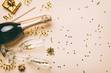 Renkli simli bir şişe şampanya, konfeti ve renkli arka planda metin için hediye kutusu alanı, üst manzara. Komik, noel ve doğum günü kutlaması.