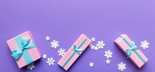 Holiday flat lay with gift boxes wrapped in colorful paper and tied decorated with confetti on colored background. Christmas, Birthday, Valentine and sale concept, top view.