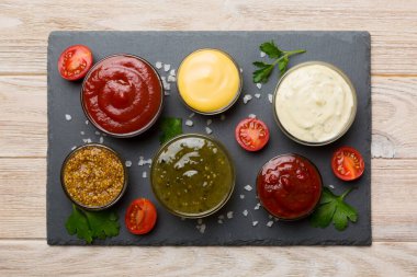 Masada bir sürü farklı sos ve bitki vardı, düz bir manzarası vardı. Tabakta soslar, sağlıklı konsept..