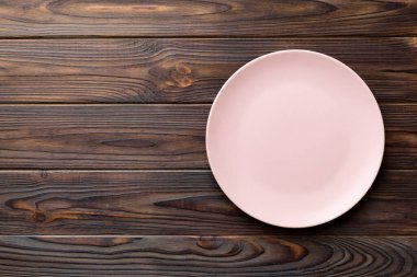 Ahşap arka planda boş pembe tabağın üst görüntüsü. Tasarımın için boş boşluk.