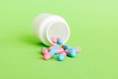 Renkli arka planda haplarla dolu plastik ilaç şişesi. İnternetteki eczane. Ağrı kesici ilaç ve antibiyotik ilaç direnci konsepti. İlaç endüstrisi..