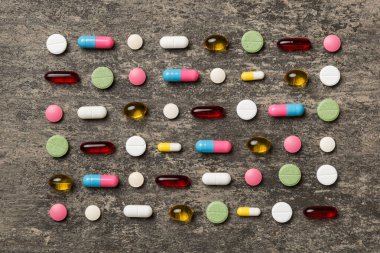 Renkli arka plan ve üst görünüm üzerine yazılmış metinler için birçok farklı hap ve alan. Renkli arka planda farklı haplar, düz yatış.