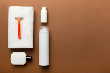 Tıraş Adam seti. Traş makinesi, havlu, losyon ve renkli arka planda tıraş köpüğü. Erkekler banyo aksesuarları üst görünüm.