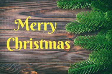 Mutlu Noeller mesajı. Ahşap zemin üzerinde köknar ağacı dallarından yapılmış çerçevenin üst görüntüsü. Tasarımınız için boş boşluklu Noel kavramı.