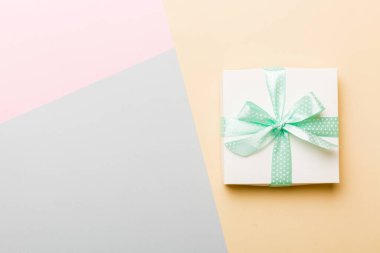 holiday handmade white present tied green ribbon bow top view with copy space. Flat lay holiday background. Birthday or christmas present. Christmas gift box concept with copy space.