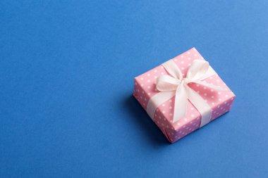 Noel 'i ya da diğer tatil hediyelerini renkli arka planda kurdeleyle renkli kağıda sardım. Şimdiki kutu, renkli tabloda hediye süslemesi, kopya alanı ile üst görünüm.