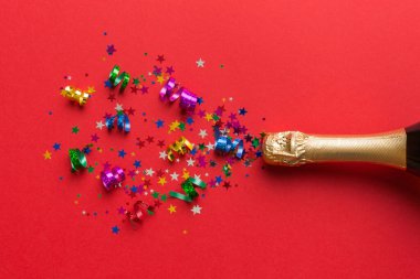 Yaratıcı düz kompozisyon, bir şişe şampanya ve renkli arka plan üzerine yazı için yer. Renkli parti flamalarıyla şampanya şişesi. tatil ya da noel konsepti.