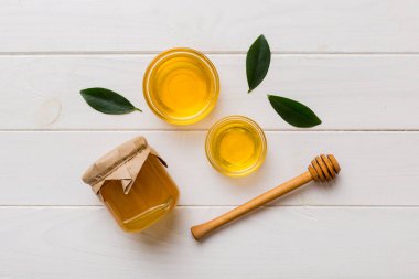 Bal kavanozu, beyaz arka plan manzaralı ve fotokopi alanı olan ahşap bal kaplama. Lezzetli bal şişesi.