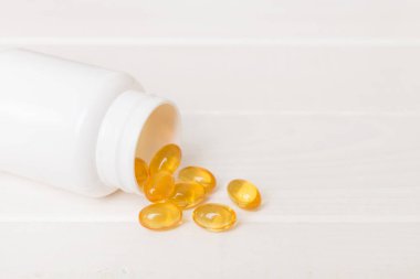 Omega-3 kapsülleri masa arkasında beyaz bir şişede yatıyor. Balık yağı tabletlerinin üst görüntüsü. Biyolojik olarak aktif katkı maddeleri. omega 6, omega 9, A vitamini, D vitamini, D3 vitamini, akşam çuha çiçeği yağı.