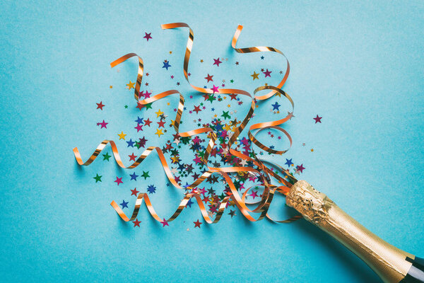Творческая плоская композиция с бутылкой шампанского и местом для текста на цветном фоне. Бутылка шампанского с красочными лентами для вечеринок. праздник или рождественская концепция.