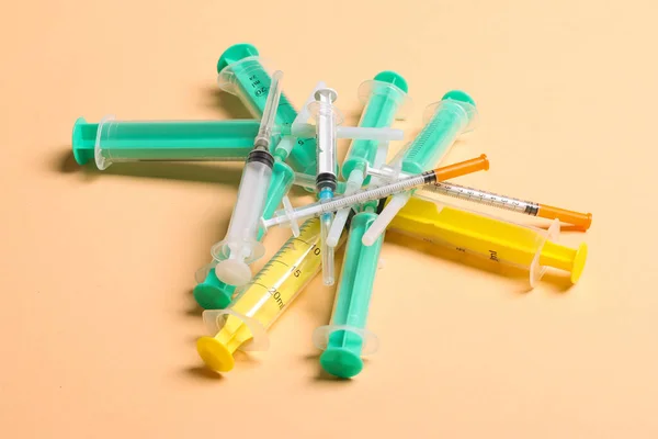 Top view of a heap of syringes and insulin syringes at orange background. Medical injection concept with copy space.